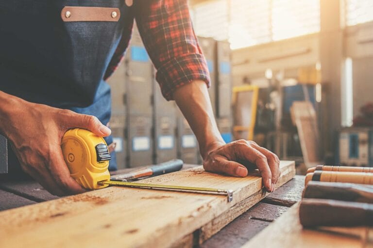 Carpenter working with equipment on wooden table in carpentry sh