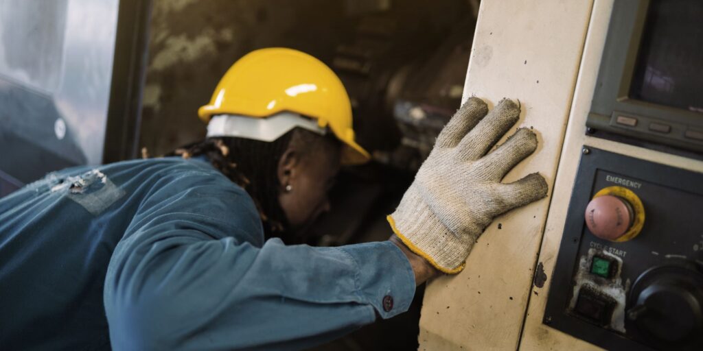 Worker inspecting industrial machinery during maintenance operations to ensure PUWER compliance.